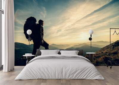 The man standing with a camping backpack on a rock with a picturesque sunset Wall mural