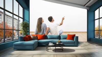 The sitting couple look the empty wall and gesture Wall mural