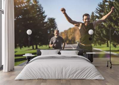 The two men running on the road in the park on the sunny background Wall mural