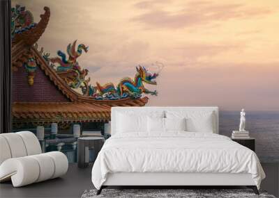 Beautiful temple overlooking coast at sunset. Chinese dragon statue on the roof. Wall mural