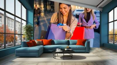 Two beautiful women holding shop bags and shopping in the city mall  Wall mural