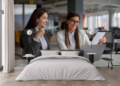 Two successful women are working on a laptop in the office. Wall mural