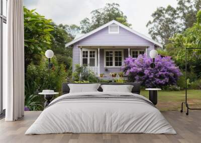 A quaint purple house stands in a flourishing garden, adorned with blooming flowers and greenery on a sunny day Wall mural