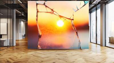 A warm sunset glows through fragmented glass, casting light on tranquil waters in the distance Wall mural