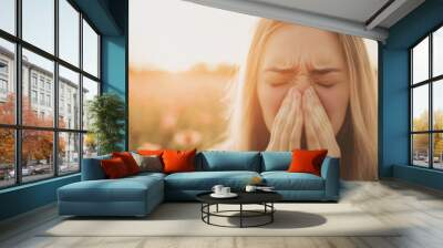 A woman experiences a sneeze in a colorful flower field bathed in warm sunlight, clearly affected by seasonal allergies in spring Wall mural