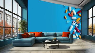 Pills, capsules on blue background with copy space, top view. Wall mural