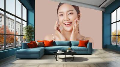 Close up perfect beauty face of young beautiful Asian woman massages her face gently with fingertips isolated on brown background. Wall mural