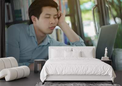 Sleepy young Asian worker with laptop computer Wall mural