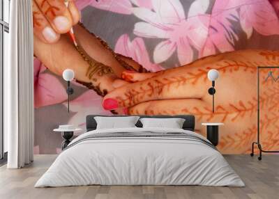 Applying Henna temporary tattoo on woman's hand Wall mural