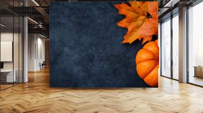 Autumn leaves and a bright orange pumpkin on a dark background during the fall season Wall mural