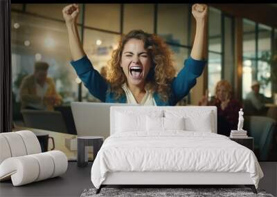 A young businesswoman in front of a laptop cheerfully celebrates success Wall mural