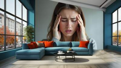 Young Woman Holding Head in Pain Due to Severe Headache at Home Wall mural