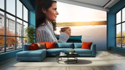 Sightseeing, smile and woman with coffee, outdoor and peace in vacation, nature and holiday. Break, travel and tea in trip, warm and calm in countryside of Finland with surprise of view of sunrise Wall mural