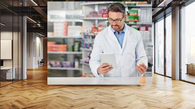 Pharmacist man, shop and reading with tablet, medicine, pills and counter for health, medication or sales. Medical professional, pharma expert and mobile digital tech in pharmacy with wellness app Wall mural