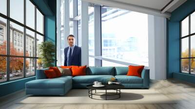 Vision, mindset and window with a business man at work, standing in his office while thinking of an idea. Corporate, growth and future with a male employee leaning against a glass wall while working Wall mural