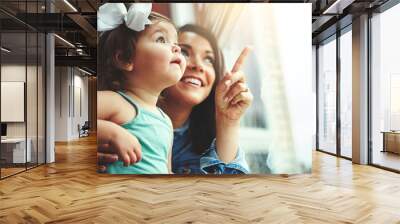 Mother, toddler and happy or home window, love and bonding with family in apartment together with girl baby. Childhood development, growth and smile or caring, woman and hand pointing in house Wall mural