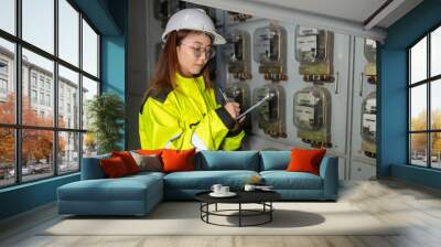 Asian electric engineer holding clipboard for checking and monitoring the electrical system in the control room,Technician thailand people working Wall mural