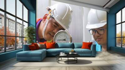 Two Asian engineer working in the boiler room,maintenance checking technical data of heating system equipment,Thailand people,Discuss the issue about the pipe pressure. Wall mural