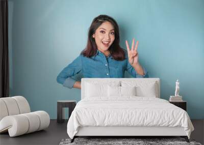 Excited Asian woman wearing a blue shirt giving number 12345 by hand gesture Wall mural