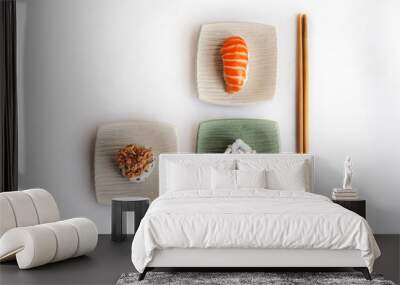 Stock photo of sushi pieces in neutral colored square plates with chopsticks, on a white background and an overhead perspective. Wall mural