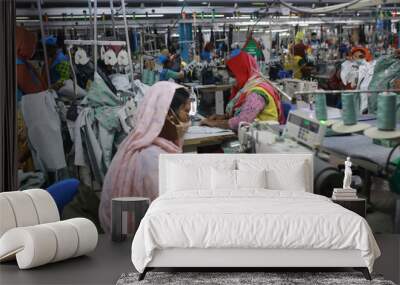 DHAKA, BANGLADESH - FEBRUARY 28, 2022: Women work at a ready-made garment factory in Dhaka, Bangladesh on February 28, 2022. Wall mural