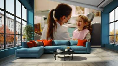 Little girl sitting in dental chair with open mouth and smiling while visiting dentist Wall mural