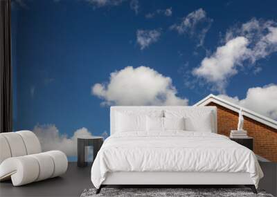 House roof against blue sky with white clouds Wall mural