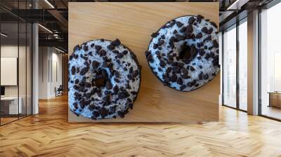 Close-up on brown donuts with white frosting and pieces of cookies Wall mural