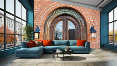 Arched window on a red brick building wall with lantern lamps on the side Wall mural