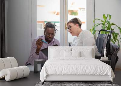 a businesswoman in a wheelchair with a disability looking at the digital tablet with her multiethnic business partner  Wall mural