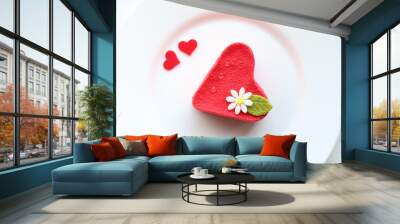 Top view of heart shaped cake with a flower on top on white plate decorated with two small hearts Wall mural