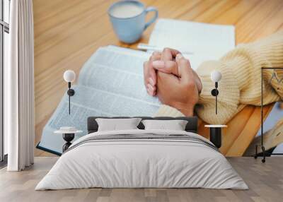 Hands, bible and praying at table, religion and Christian worship in home at desk. Closeup, holy book and woman in meditation for God, Jesus and Christ for faith in spiritual gospel, praise or hope Wall mural