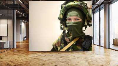 Woman in military clothes with mask over light background and with vignetting. Female soldier in camouflage Woman at war concept. Portrait of female protesting activist in green balaclava. Wall mural