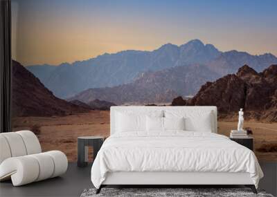 Mountain landscape in a stone desert with silhouettes of high hills at sunset. Extreme adventures on tourist transport in desert, off-road trips and active leisure for tourist in Egypt. Wall mural