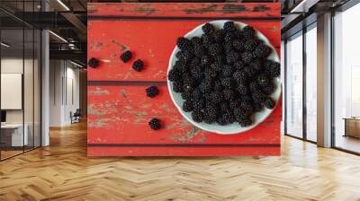 Ripe blackberries in a white plate on a red wooden background close-up. Fresh black berries still life. Wall mural