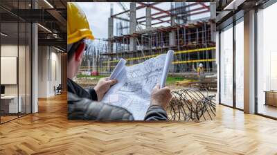 Construction worker reviewing blueprints at a building site. Wall mural