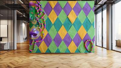 Purple Mardi Gras mask on a green, purple, and yellow diamond patterned background with beads. Wall mural