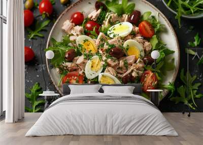 A flat lay of a classic tuna salad with mixed greens, cherry tomatoes, hard-boiled eggs, olives, and tuna chunks, arranged on a white ceramic plate. Wall mural