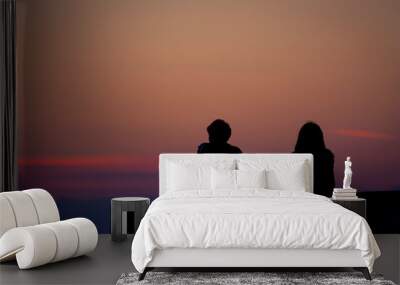 silhouette of a young couple watching the sunrise over the sea Wall mural