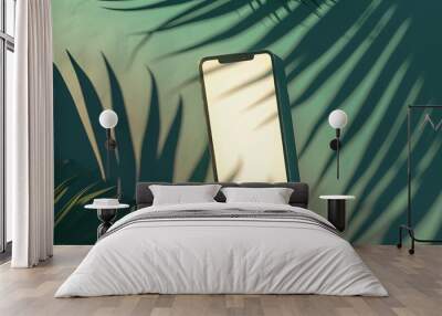 Smartphone mock-up with a white blank screen and a palm leaf shadow isolated on a green mint background at sunset. Creative layout. mockup top view, flat lay Wall mural