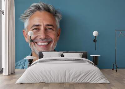 A middle-aged man with gray hair on a blue background with a pleasant smile. Health and beauty, healthy teeth. Wall mural