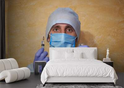 doctor holding a syringe in his hand,medical worker in a medical mask with a syringe Wall mural