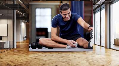 Fitness, man and stretching legs in gym for health, mobility and flexibility. Sports, wellness and happy male warm up or preparing for training, exercise or workout in fitness center for healthy body Wall mural