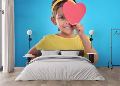 Portrait, heart cut out and girl with smile, joyful and cheerful against blue studio background. Face, female kid and young person with symbol for love, happiness and joyful with development and sign Wall mural