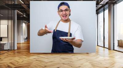 Asian barista man showing excited expression while holding empty dinner plate Wall mural