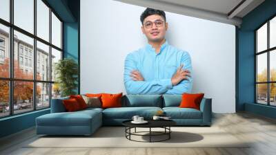 Asian man standing with arms crossed and smiling at camera isolated over white background Wall mural