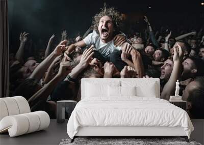 Energetic crowd surfing at a concert with an excited person being carried by a group of people in a dimly lit venue. Wall mural