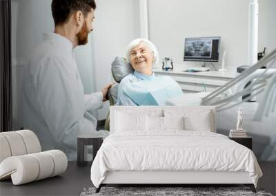 Beautiful elder woman with healthy smile sitting during the consultation with dentist at the dental office Wall mural