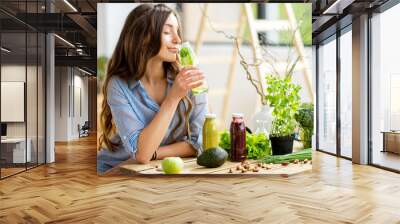 beautiful woman sitting with drinks and healthy green food at home. vegan meal and detox concept Wall mural