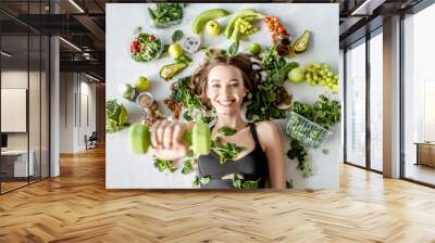 Beauty portrait of a sports woman surrounded by various healthy food lying on the floor. Healthy eating and sports lifestyle concept Wall mural